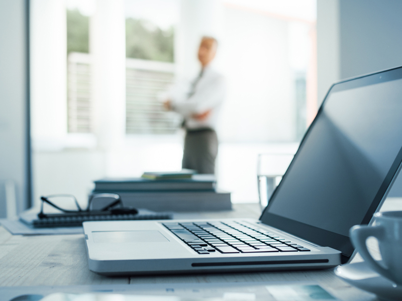 Laptop with blurred businessman on background