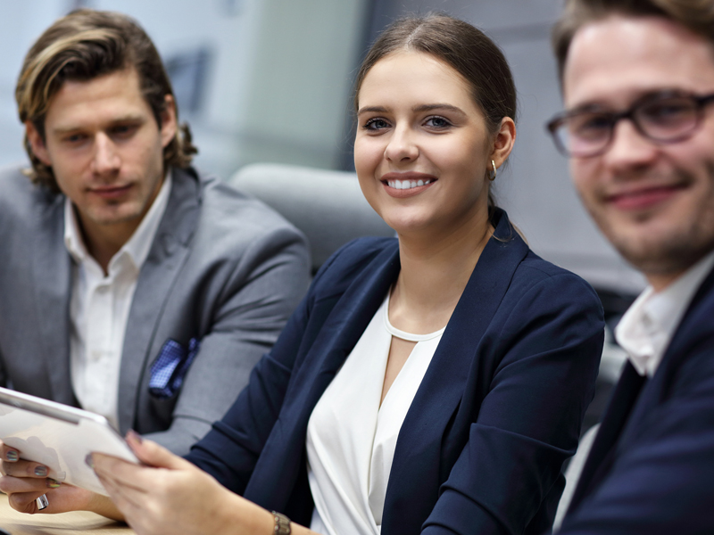 three persons in business attire smiling 