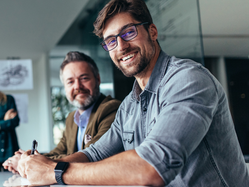 two man in business attire smiling 